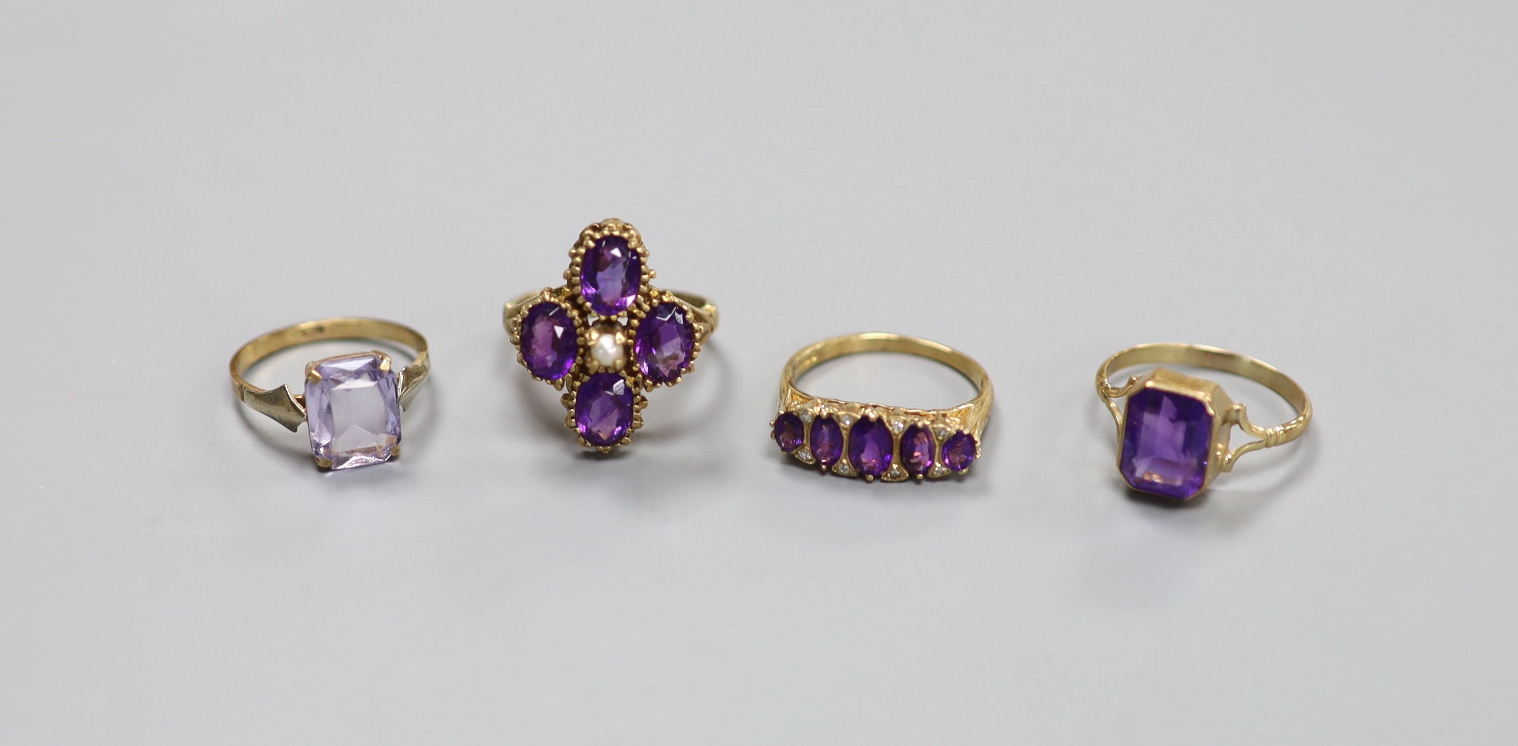 Three assorted 9ct and amethyst set dress rings, including amethyst and diamond and amethyst and seed pearl and one 9ct and amethyst paste ring.